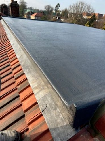 Flat roof with a smooth waterproof membrane over tiled roof edges.