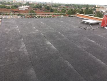 View of a flat rooftop with a skylight and cityscape in the background.