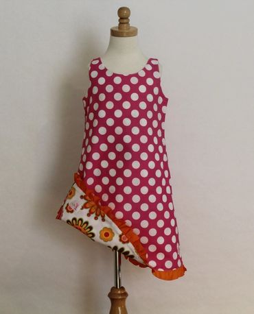 Pink polka dot sleeveless dress with floral ruffle hem on mannequin.