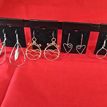 Variety of wire earrings displayed on black cards against a red background.