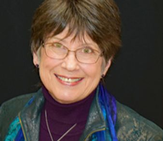 Smiling elderly woman with glasses and short hair.