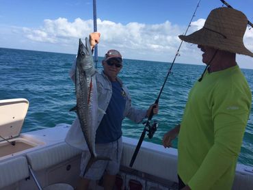 Two men on a boat showing off a large catch during a fishing trip.