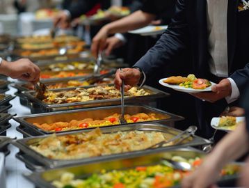 People serving themselves food from a buffet with various dishes.