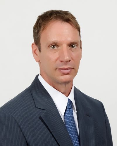 Professional man in a suit and tie against a plain background.