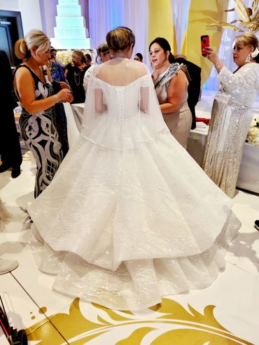 Bride wearing her custom bridal gown, with bustle, at her gypsy wedding. Family surrounds her.