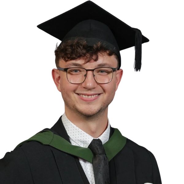 Young man smiling in graduation attire with cap and gown.