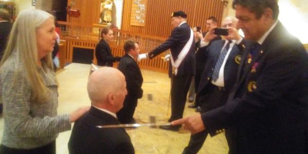 Man being knighted in a formal ceremony.