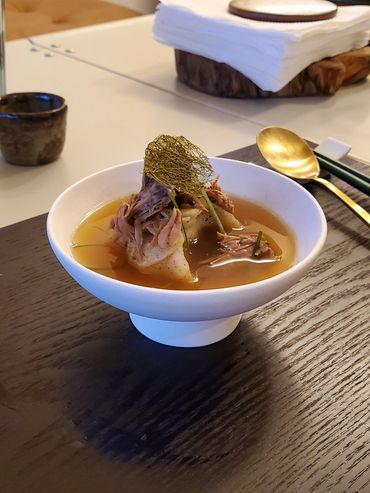 North Korean style Mandu in soup with Sea trumpet(Gam Tae) in Porcelain bowl with high feet.