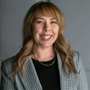 Smiling woman with blonde hair in a checkered blazer.