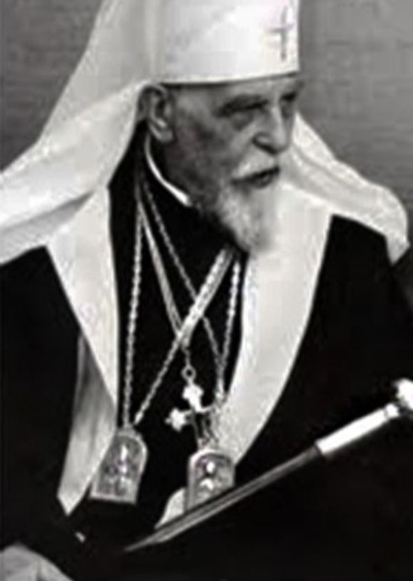 Elderly religious leader in ceremonial attire with a staff.