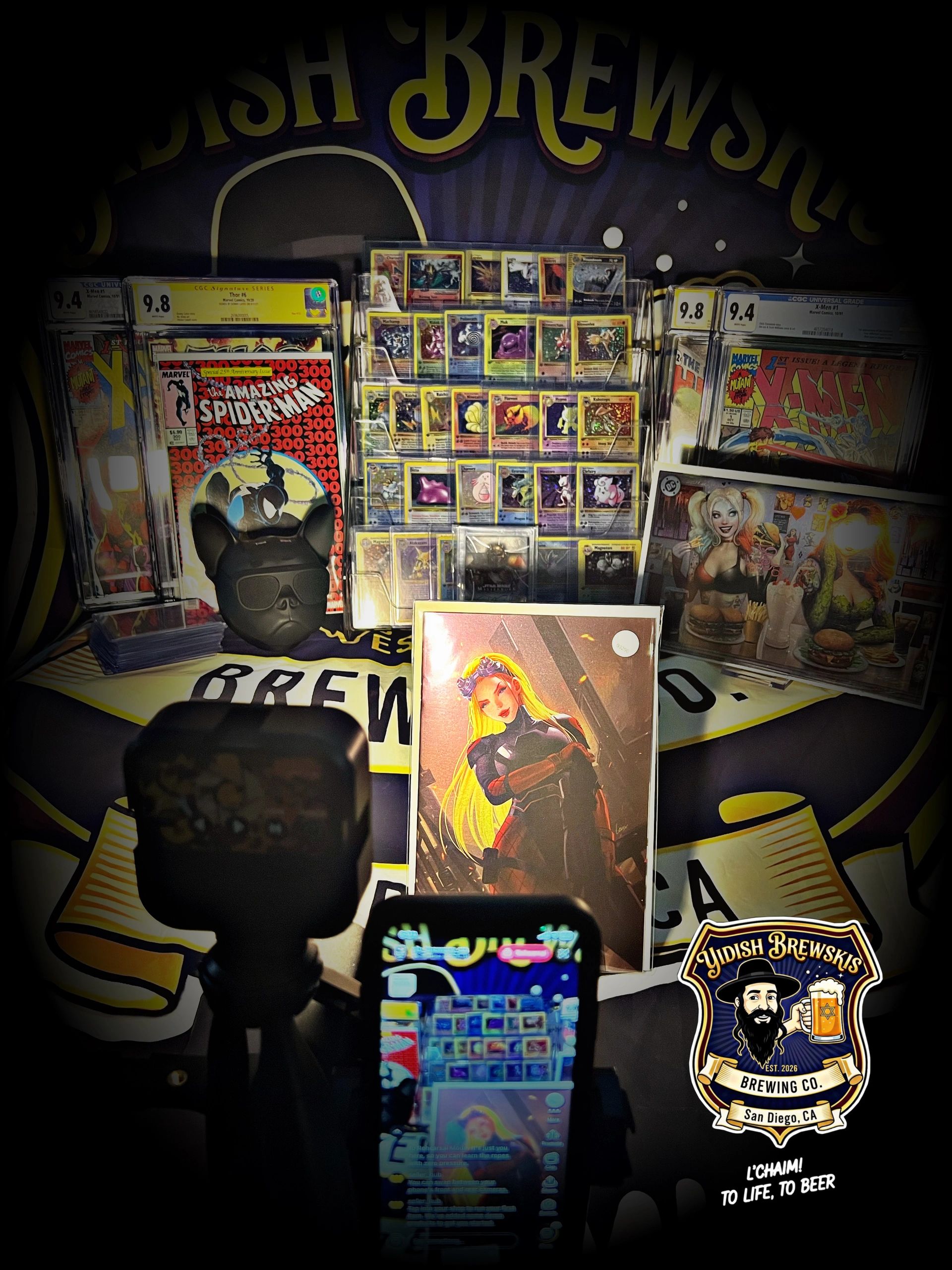 A collection of graded comic books, Pokemon cards, and a phone recording the setup.