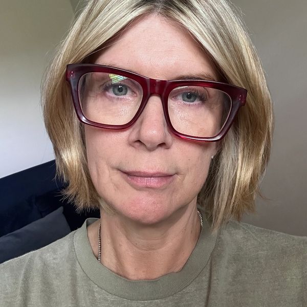 Woman with blonde hair and large red glasses.
