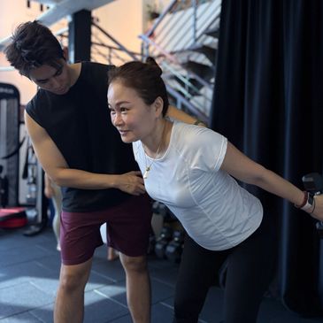 coach guiding a busy mom how to perform dumbbell tricep kickback for better posture and anti-ageing