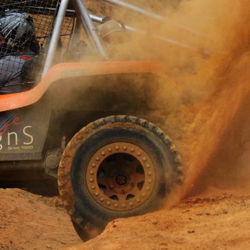 Sand buggy stuck in a rut with dirt flying out the back
