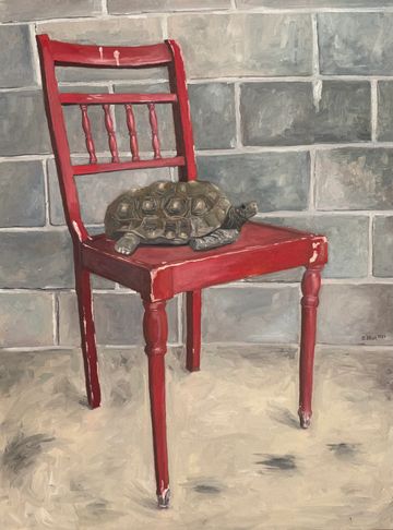 Tortoise on a red chair against a gray brick wall.