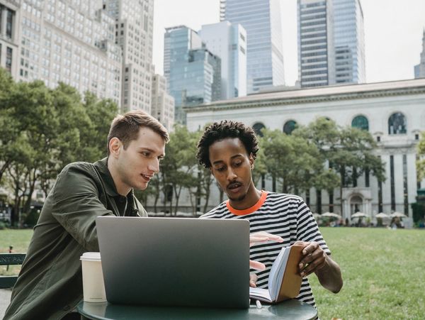 Two students learning from their laptop and taking notes
