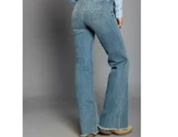 Rear view of person wearing blue flared jeans and beige shoes.