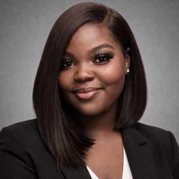 Professional headshot of a smiling woman with straight hair and a black blazer.