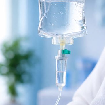 Close-up of an IV drip chamber with liquid flowing inside.