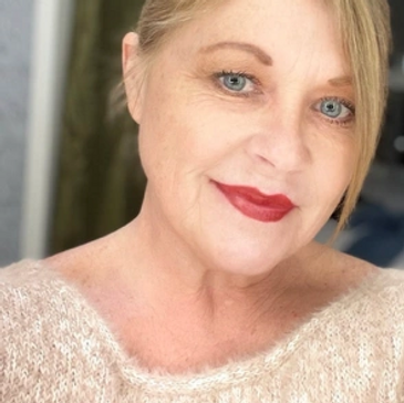 A woman with blue eyes and red lipstick smiling at the camera.