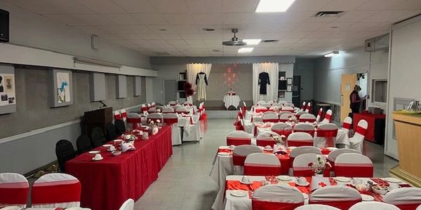 A banquet hall decorated with red and white table settings for an event.