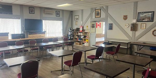 Empty community room with tables and chairs arranged in a U-shape.