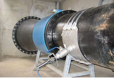 Large industrial pipeline with inspection equipment in a concrete facility.