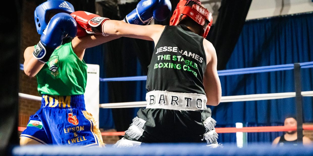 Two youth boxers in the ring, one throwing a punch at the other.