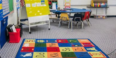 Colorful early childhood classroom with alphabet rug and learning stations.