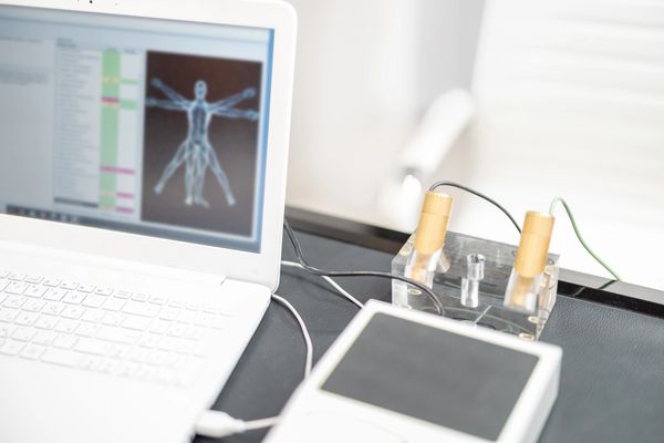Laptop displays human body scan results with medical devices on a table.
