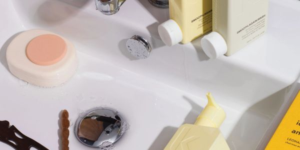 sink with hair pins, soap, bottles of shampoo and conditioner on the sink and in the sink