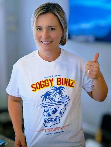 A woman giving the thumbs up wearing a t-shirt with a skull design.