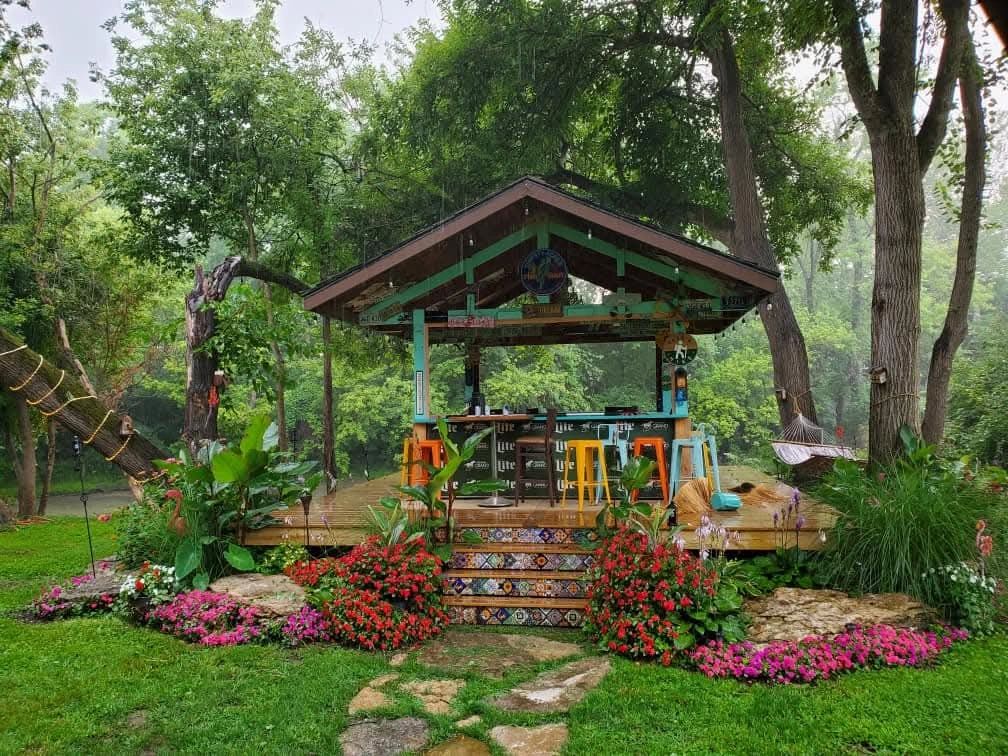 A colorful outdoor bar surrounded by lush greenery and vibrant flowers.