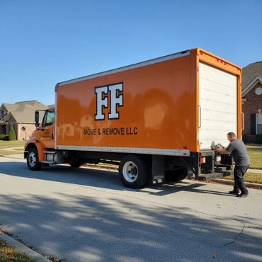 Man operating an orange moving truck in a suburban neighborhood.