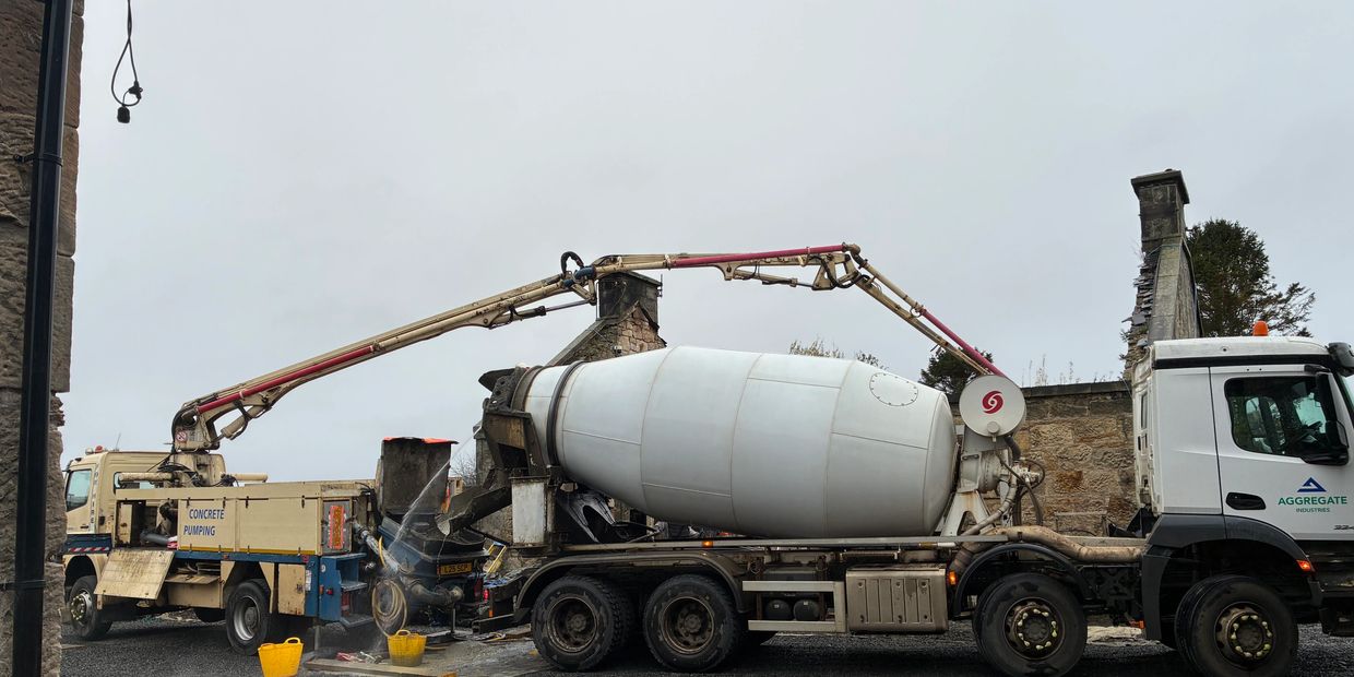 Concrete mixer truck and pumping machine at work on a gravel driveway. using a 20 meter boom pump. concrete boom pump hire available in Edinburgh and Glasgow