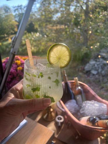 Hand holding a refreshing lime cocktail with a wine bucket in the background.