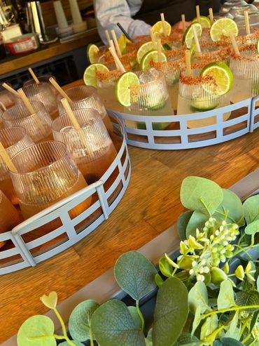 Two trays of refreshing cocktails garnished with lime slices and wooden stirrers.