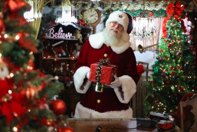 Santa Claus holding a gift in a festive room.
