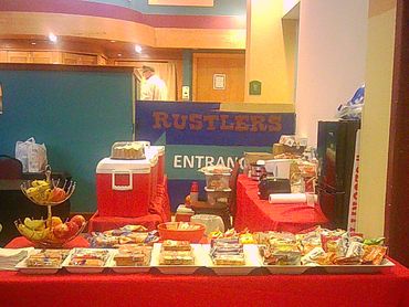 A table with snacks and coolers at an event entrance.