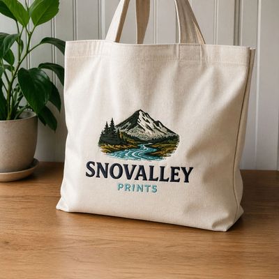 Canvas tote bag with mountain and river embroidery and "SNOVALLEY PRINTS" text.