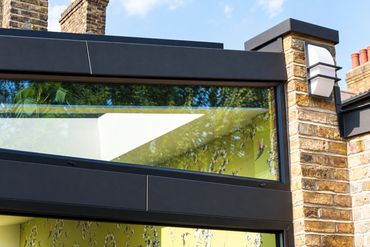 Dark metal fascia, high-level glazing and reclaimed brickwork on the Newham extension.