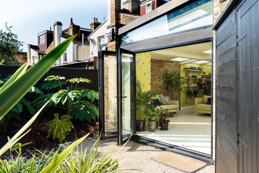 Garden view of the finished Newham extension, with black glazing and reclaimed brickwork.