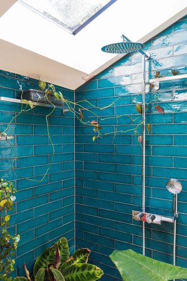Chrome shower fittings against teal wall tiles beneath a rooflight in the Newham shower room.