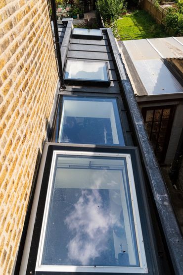 Roof glazing along the side-return extension beside the original brick house in Newham.