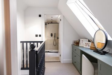 Loft landing with dark timber balustrade, dressing area and bathroom beyond.