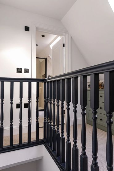Finished loft landing with dark timber balustrade and fitted cupboards beneath the roof slope.