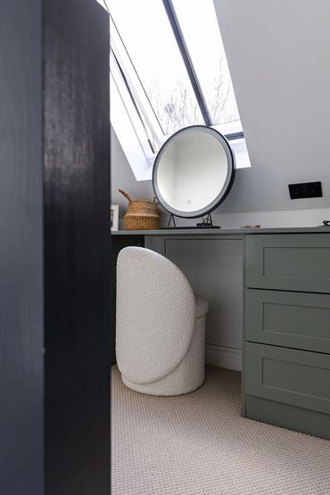 Fitted dressing table with drawers, a round mirror and seating beneath the roof slope.