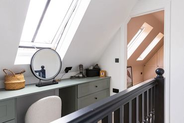 Loft dressing area with a fitted desk, rooflight and bedroom doorway beyond.