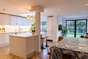 Finished kitchen with central island, dining area and black garden doors.
