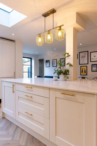 Kitchen island with pendant lighting, rooflight and dining area beyond.